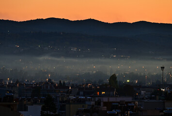 Beautiful view of foggy weather over the city in the dark at sunset © Adam Leszko/Wirestock Creators