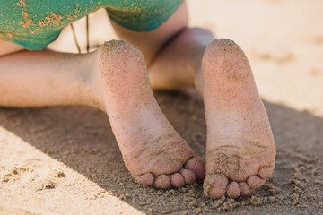 Unrecognizable kid with sandy feet