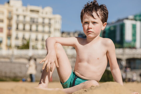 Thoughtful boy on sandy beach looking away