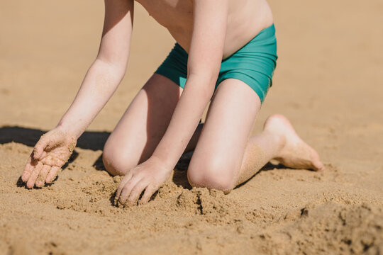 Unrecognizable boy playing with sand