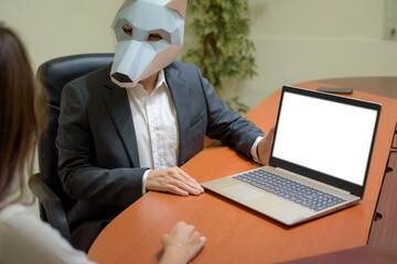 Businessman in a wolf mask talking to a colleague and showing the laptop with copy space