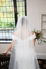 Vertical shot of a bride in a beautiful wedding dress walking down the stairs © Mark Battista/Wirestock Creators