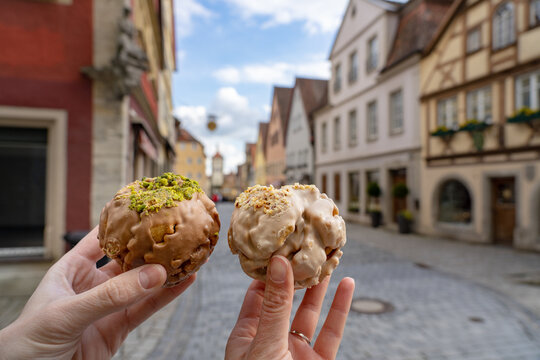 eating traditional schneeball snowball cake together the cake of the romantic Rothenburg ob der Tauber with timbered Fachwerkhaus syle houses in Bavaria Germany