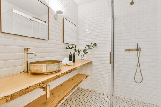 Interior of minimalist bathroom with wooden shelves and shower cabin