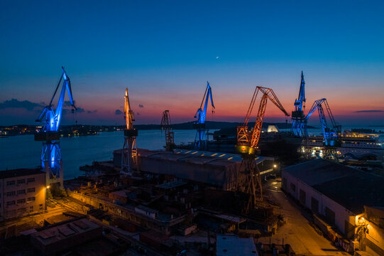 Aerial view of industrial cranes coloured with Ukrainian colours flags in memory of Russian invasion in Ukraine, Pula, Croatia.