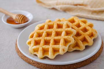 Waffles on white plate and honey in bowl