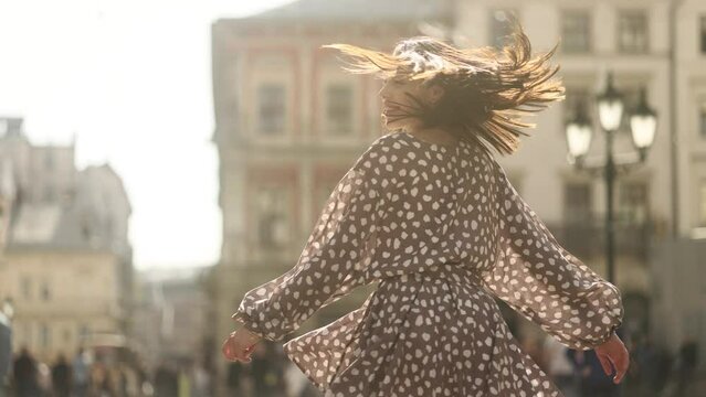 Portrait of attractive young woman with flying hair walking down the street. Close up view of happy girl.