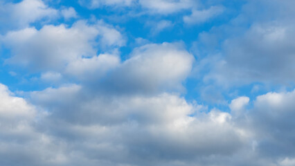 Naklejka na ściany i meble Blue sky background with clouds. White cumulus clouds in blue sky. Cloudy weather, cloudscape, copy space. Space for text.