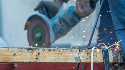 Close-up view of a worker working with angle grinder. Electric wheel grinding on steel structure. Sparks.