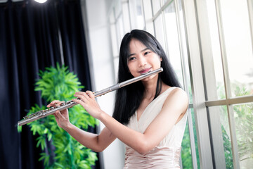 Flute classical instrument profestional player playing song.  A young and elegant Asian woman plays...