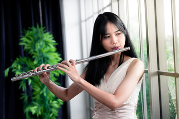 Flute classical instrument profestional player playing song.  A young and elegant Asian woman plays...