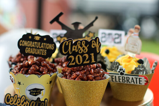Selective closeup of 2021 graduation celebration decorations, sweets with yellow cups on the table