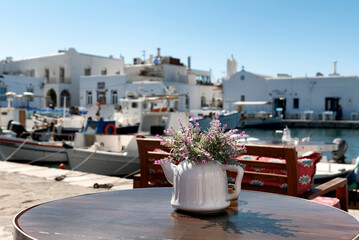 Flower arrangement in teapot on the table of a taverna in Paros - obrazy, fototapety, plakaty