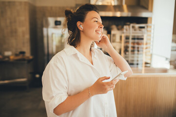 Young woman listening to music online using her smartphone and wireless earphones.