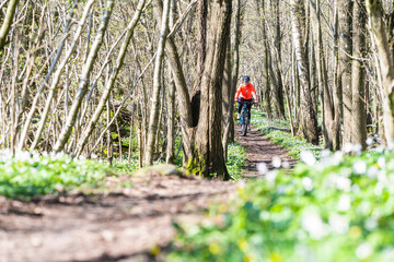 Woman cycling on trail in forest