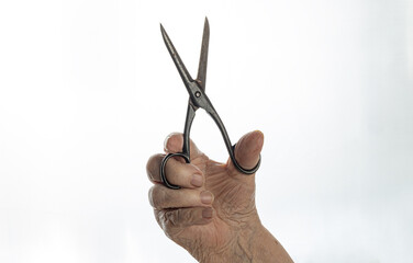  The elderly person's hand with open scissors pointing upwards.