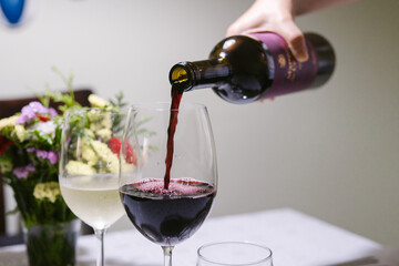 Hand pouring red wine into a glass