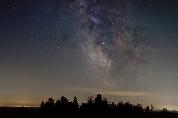 Fototapeta na wymiar The galactic core of Milky Way over silhouette of trees on the Schliffkopf, Black Forest, Germany