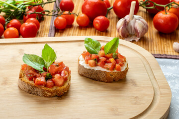 bruschetta with tomato, ricotta and basil, on a wooden board
