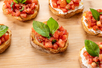 bruschetta with tomato, ricotta and basil, on a wooden board