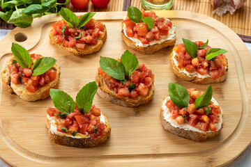 bruschetta with tomato, ricotta and basil, on a wooden board