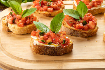 bruschetta with tomato, ricotta and basil, on a wooden board