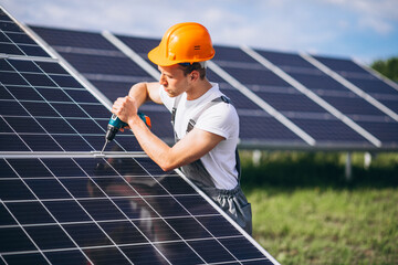 Repair man with drill in the field with  solar panels