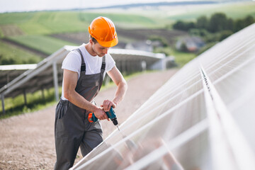 Repair man with drill in the field with  solar panels