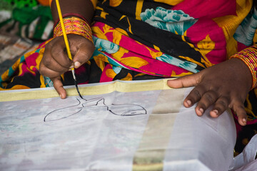 Closeup of a woman's hands as she paints on a piece of cloth