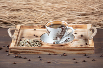Fototapeta na wymiar Hot coffee in a coffee cup and many coffee beans are placed around it, on a wooden table in a warm, light atmosphere, on dark background, with copy space.