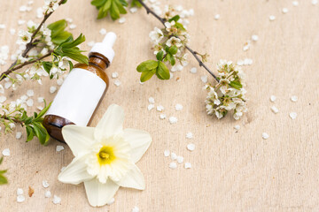 Fototapeta na wymiar Elegant cosmetic jar with cherry blossoms on white background. Side view