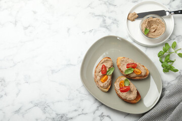 Slices of bread with delicious pate, tomatoes and basil on white marble table, flat lay. Space for text