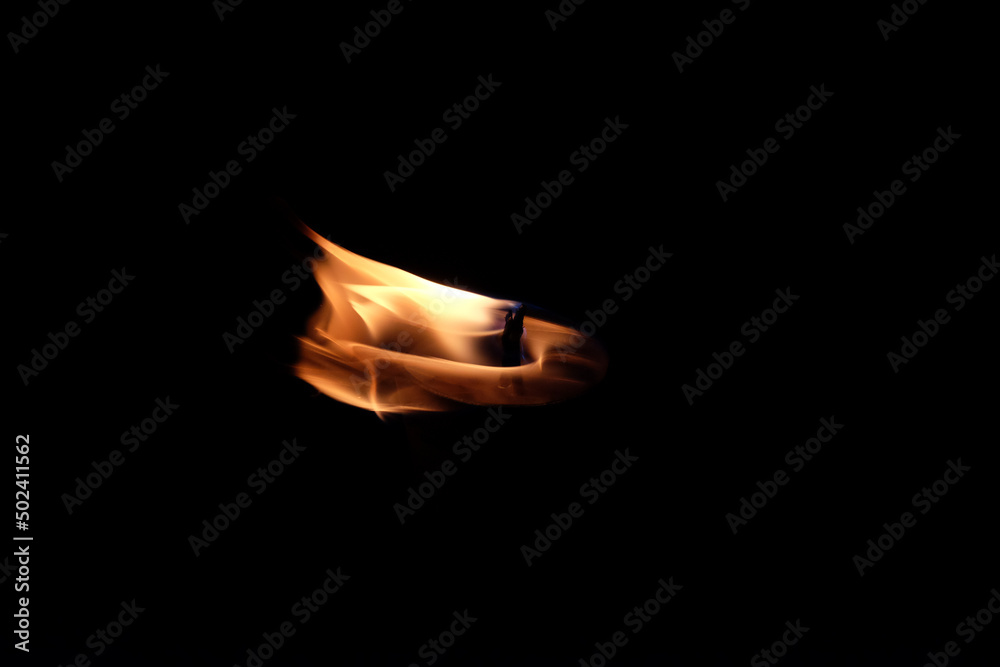 Wall mural Closeup shot of a fire on a candle isolated on a black background