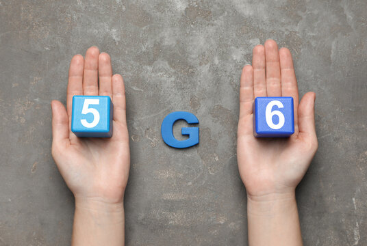Internet concept. Woman holding blue wooden cubes and letter on grey table, top view