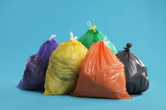 Trash bags full of garbage on light blue background