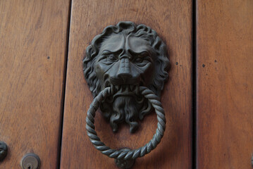 Closeup of a metallic knocker with a lion head on a wooden door in Cartagena, Colombia