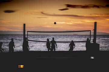 Beautiful shot of silhouettes of people playing volleyball during the sunset
