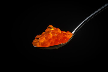Fresh red caviar in a spoon on a black background