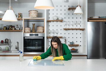 Young landlady is making a big cleaning for the apartment she is renting out, to be clean for the new tenants to whom she has rented out the apartment. Teenage girl or woman rubbing the kitchen.