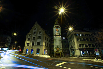 Clocktower between buildings by a street at night
