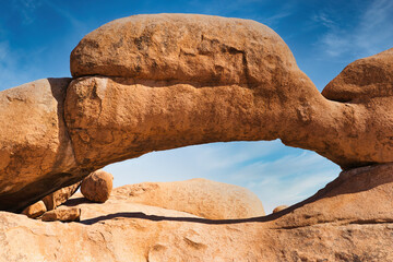 Stone arch of famous Spitzkoppe National Park in Namibia creating national symbol for this african country, with no people in the shot forming a peaceful and powerful scene of the raw power of nature - obrazy, fototapety, plakaty