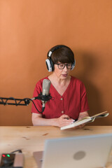 Middle-aged female radio presenter talking into the microphone and reading news - radio broadcast...