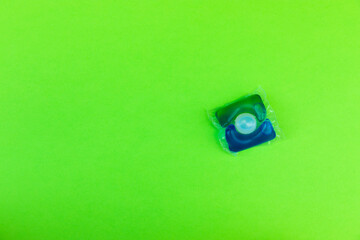 Capsule of gel for washing clothes in a washing machine with detergent on a green background. View from above. Space for copy.Cleanliness concept.