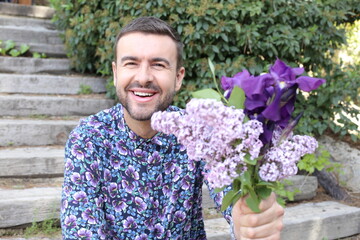 Cute man holding purple floral arrangement 