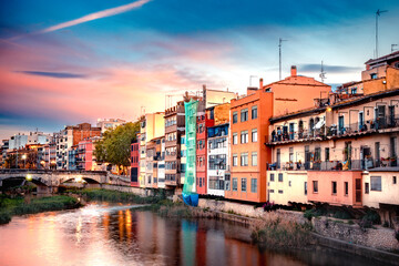 Beautiful view of the medieval city of Girona Spain with canal and historic colorful buildings seen at sunset.