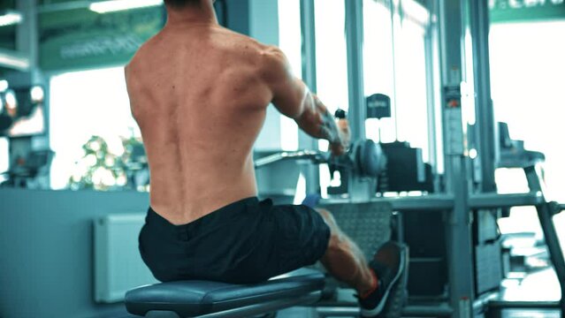 Intensive workout in gym, man doing cable row exercise, using sports machine