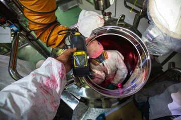 Worker hand holding gas detector inspection safety gas testing at front manhole stainless tank