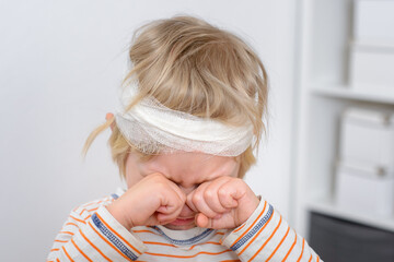 Child with bandaged head crying, child abuse.
