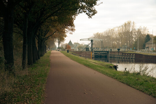Scenic view of a bike lane next to green trees and a river in Helmond, Netherlands