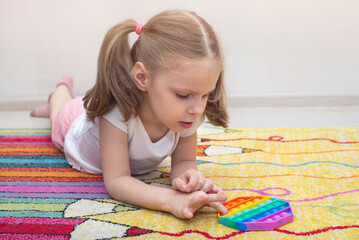 A girl plays with a popular toy multi-colored pop it in the form of an octahedron